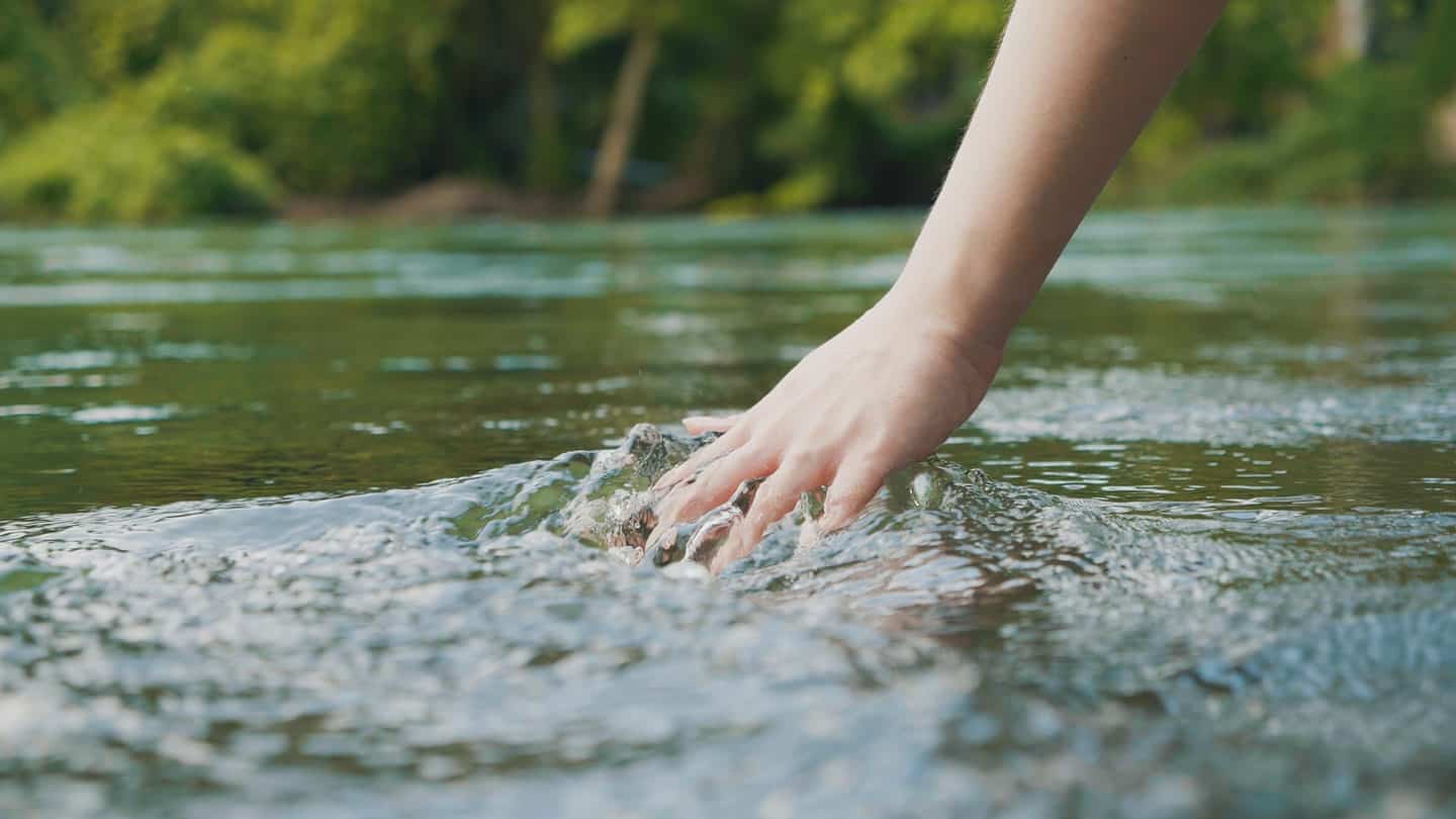 La mano della donna che accarezza l'acqua limpida